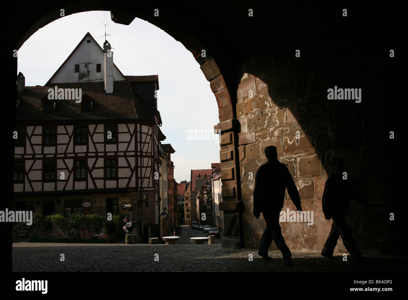 Two silhouetted man walking through the medieval Tiergartnertor gate to Albrecht Durer's House in Nuremberg, Germany Stock Photo