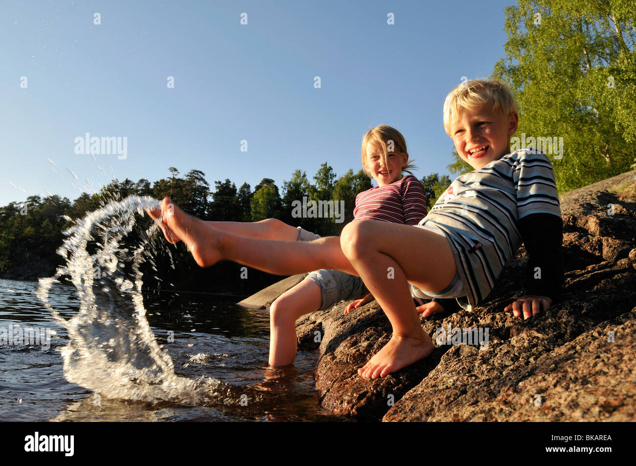 Girl and boy splashing around with feet, Norrkoeping, Ostergotlands Lan, Sweden Stock Photo