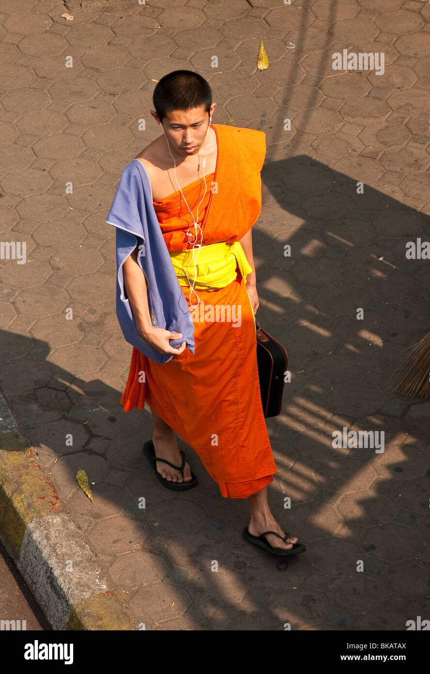 Buddhist monk with iPod earphones and laptop computer case; Chiang Mai, Thailand. Stock Photo