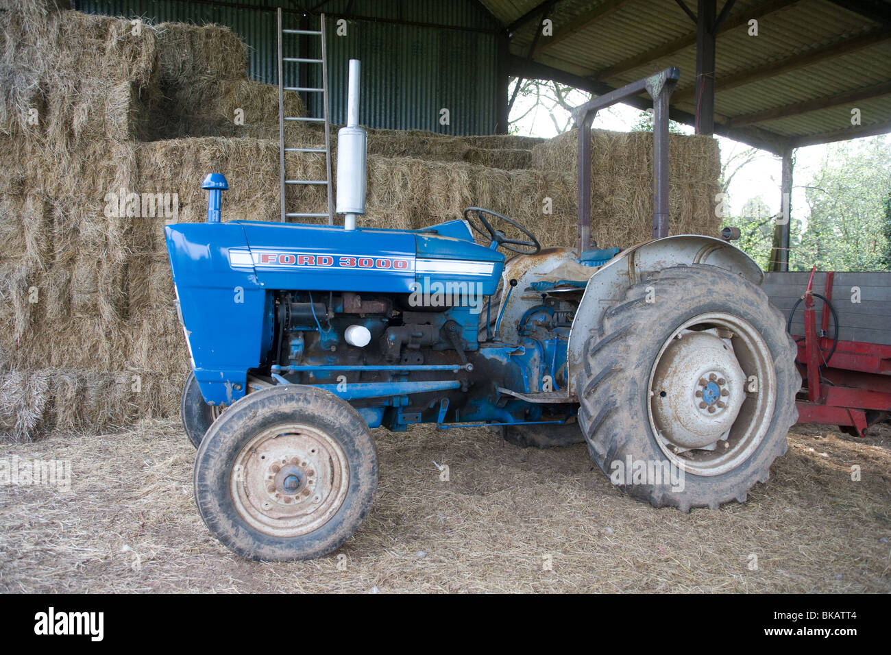 Old Ford tractor parked in a hay shed Stock Photo