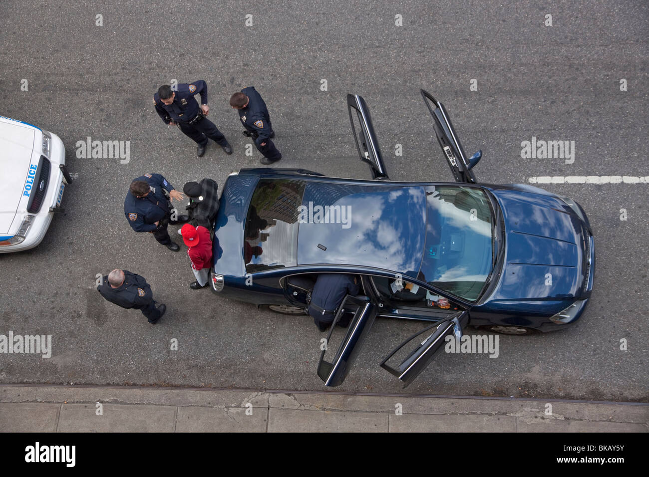 Police officers stop a car with two male suspects in New York City and search their car. Stock Photo