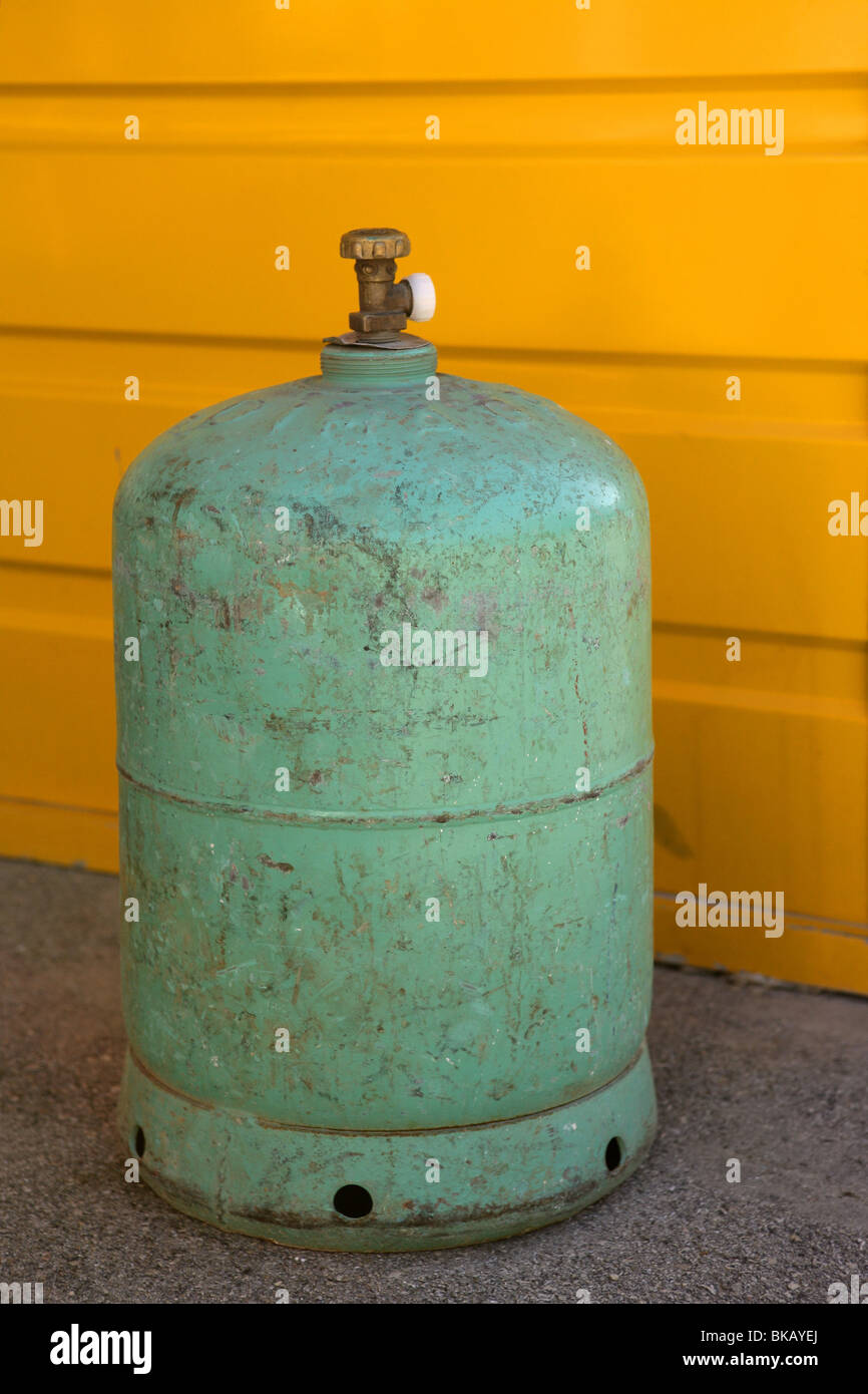 Camping gas container, green over yellow background Stock Photo