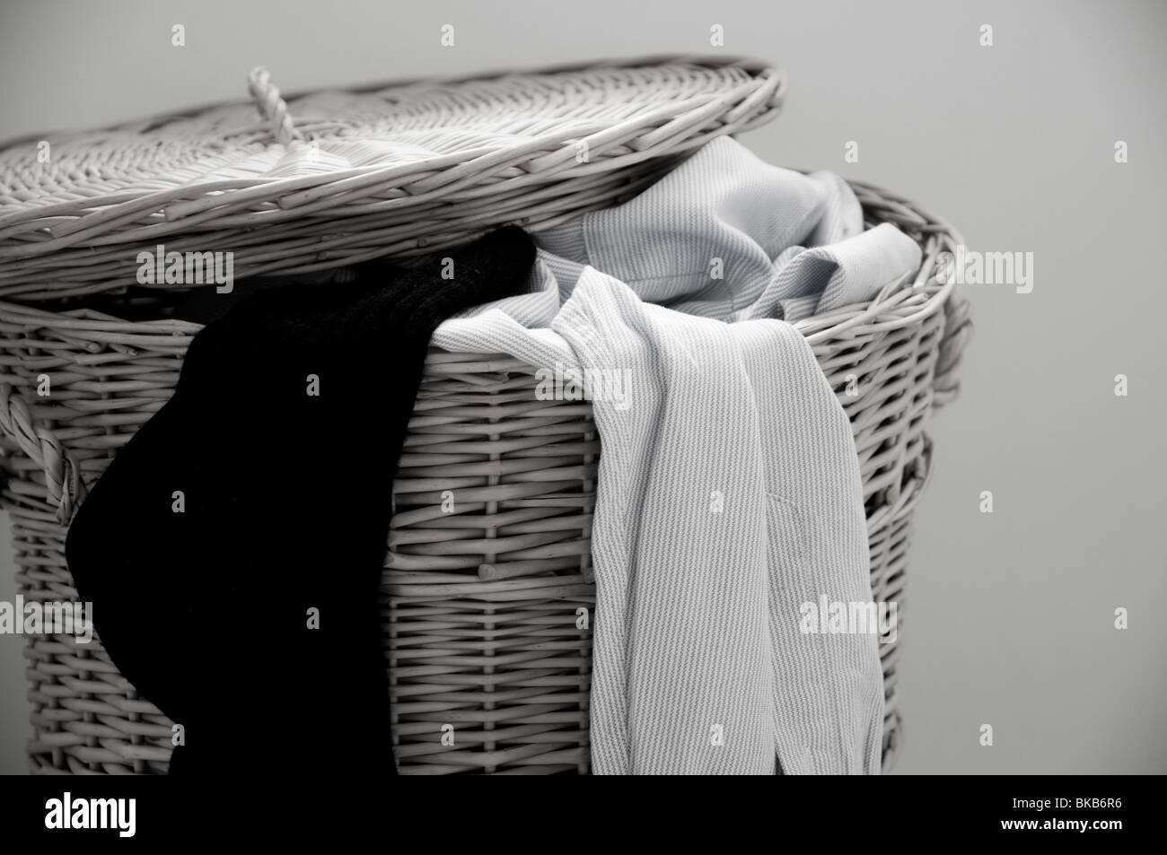 Clothes ready for the wash, spilling out of a willow washing basket.  (B&W) Stock Photo