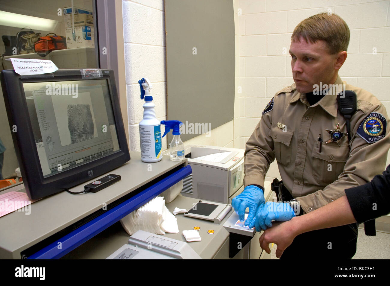 Jailer fingerprinting a suspect using a modern scanner during the