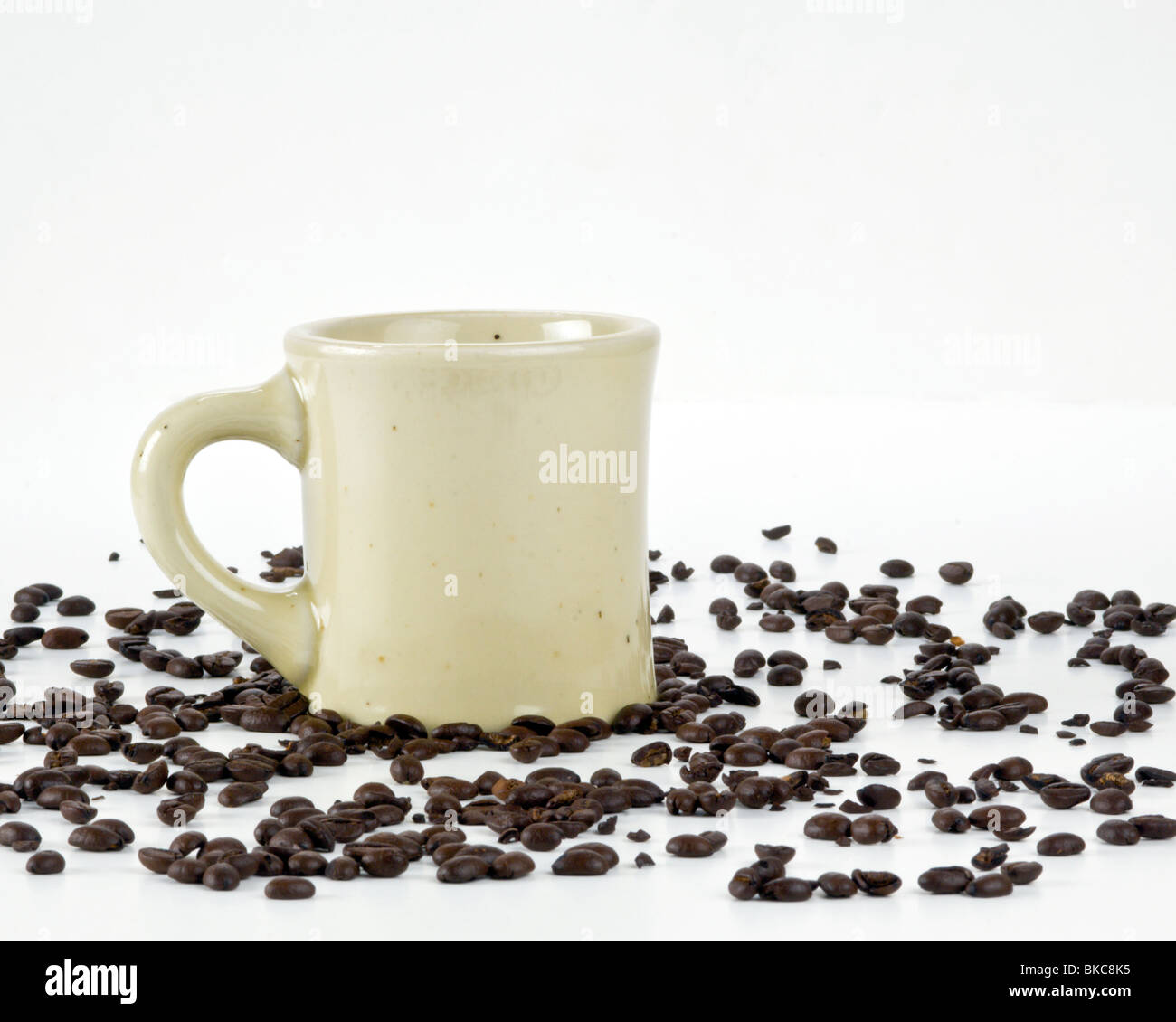 Iconic Coffee Mug with scattered coffee beans on white background Stock