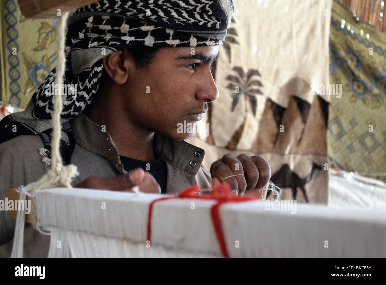 Young Bedouin man weaving inside tent Stock Photo