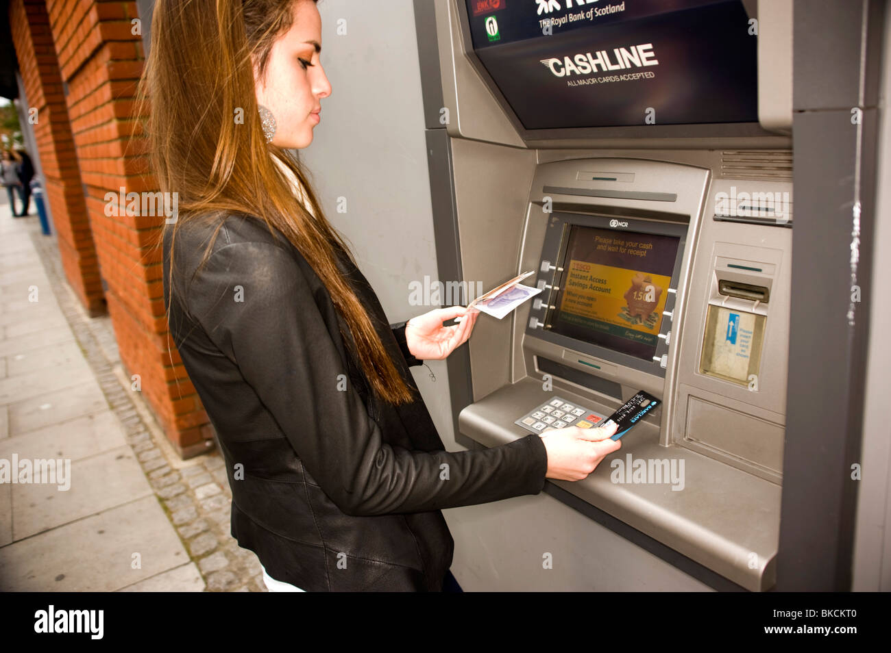 Teenage girl at ATM cash point machine with drawing money Stock Photo
