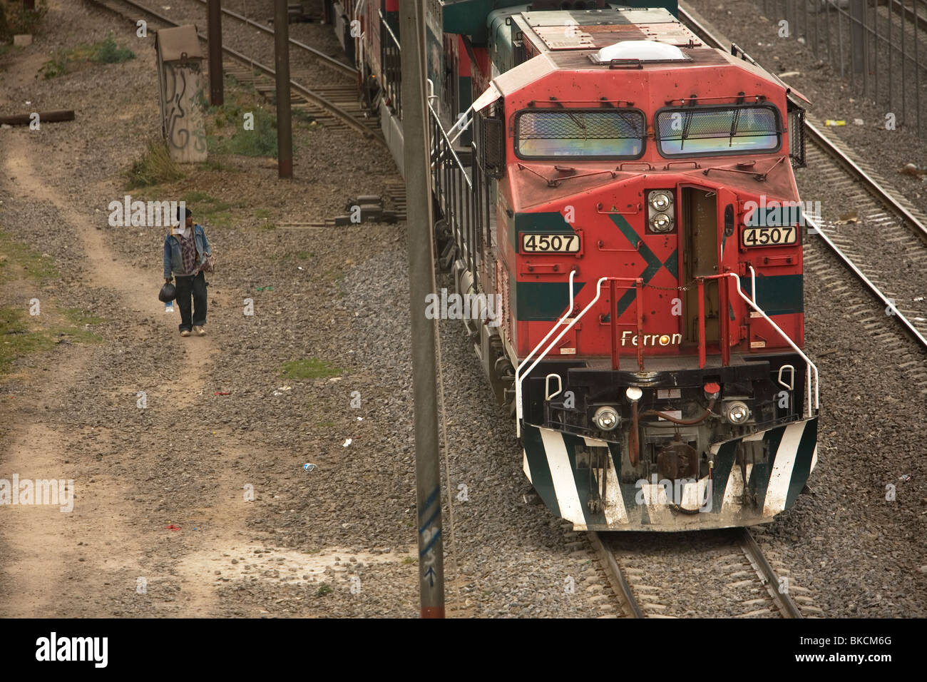 An undocumented Central American migrant traveling across Mexico to reach United States walks by a cargo train in Mexico City Stock Photo