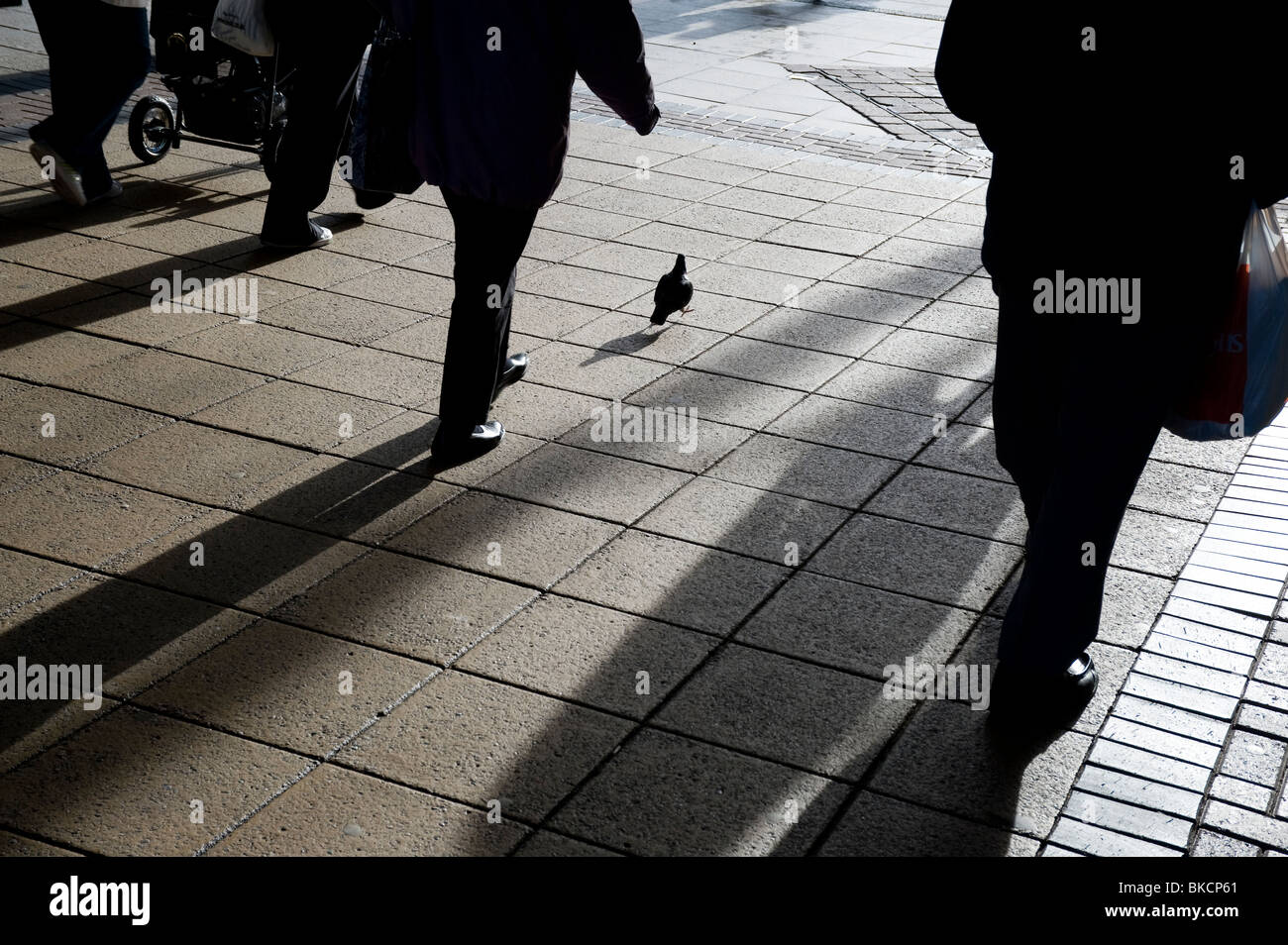 Silhouettes of people walking along a city pavement Stock Photo - Alamy