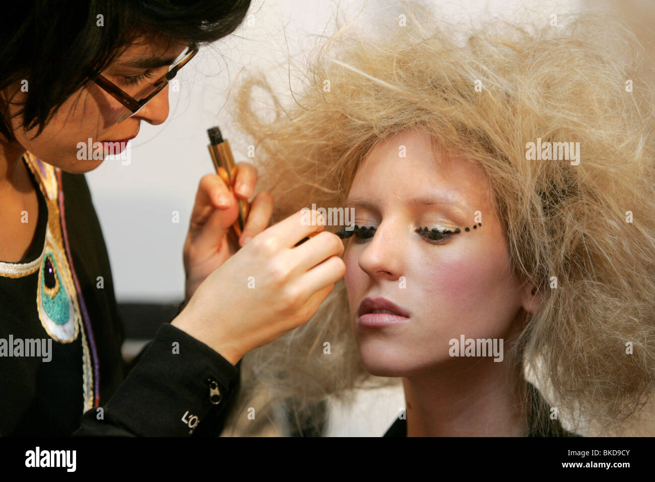Make-up artist applying make-up on female model. Stock Photo
