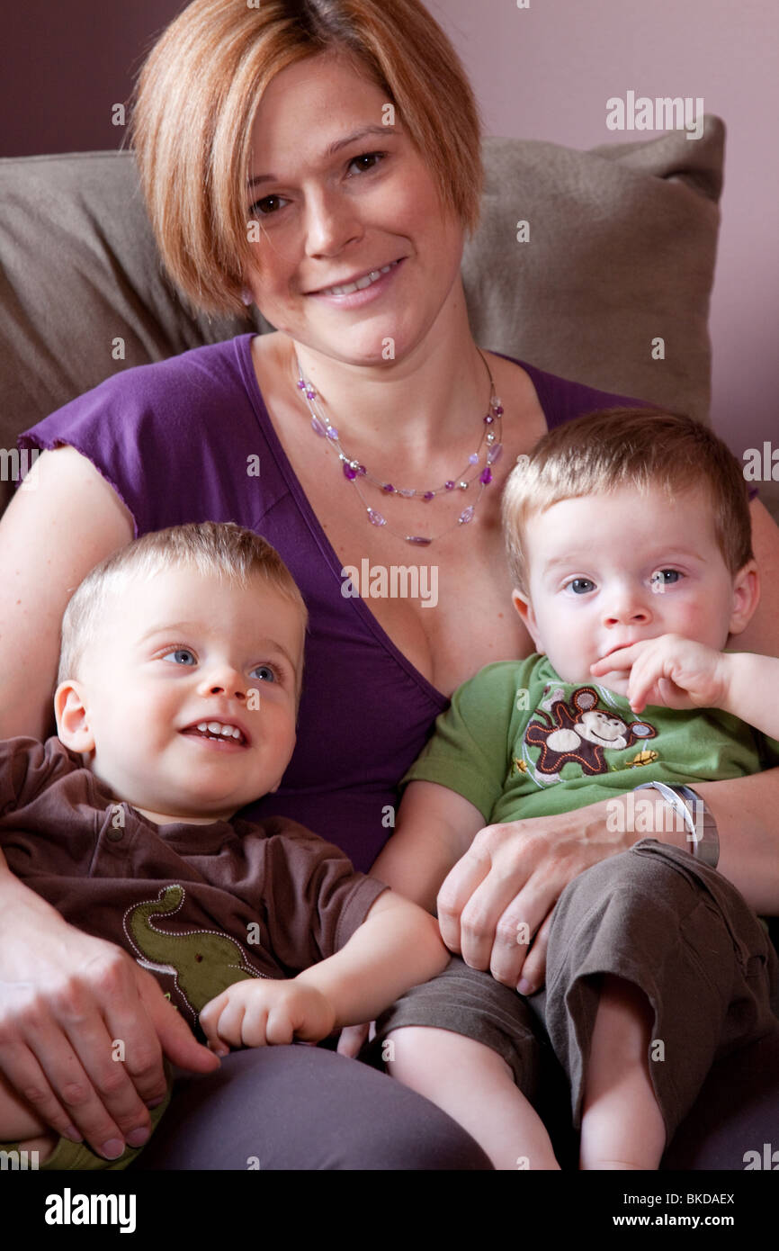 Caucasian woman sits on the couch with her twin boys Stock Photo Alamy