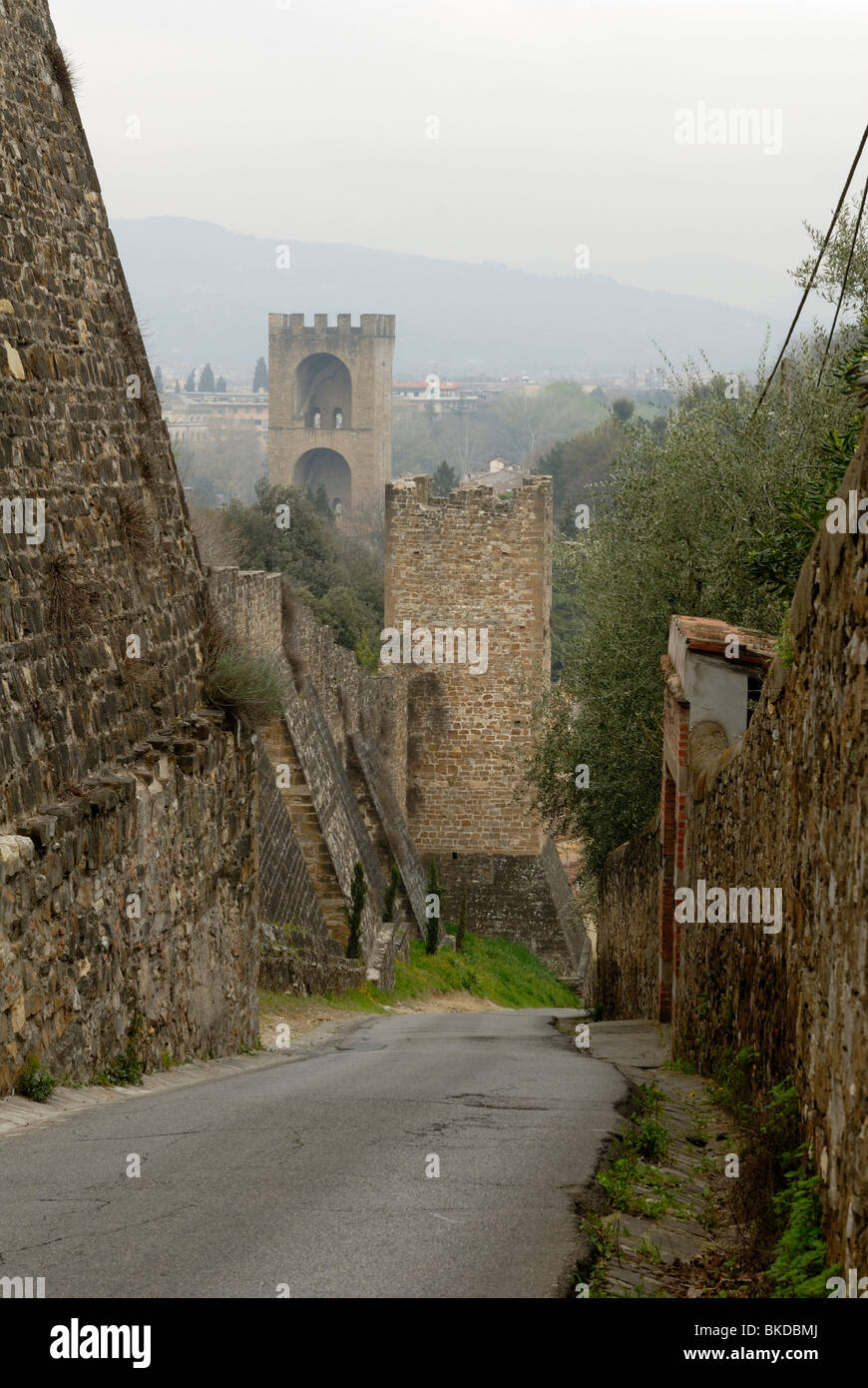 A spectacular misty spring morning view downhill along Via di Belvedery. On the left is the city walls and towers, dating from.. Stock Photo
