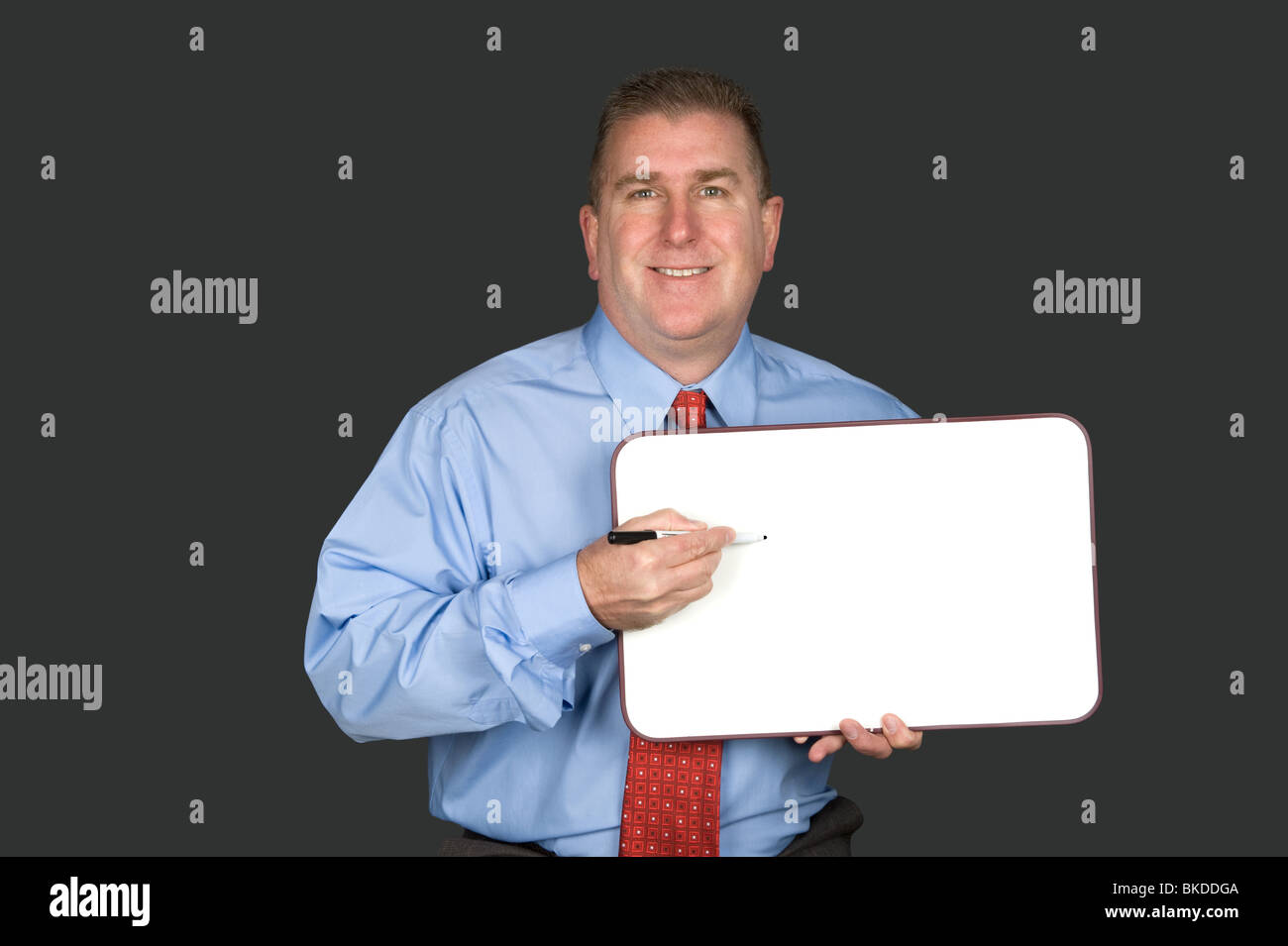 A businessman holds a blank whiteboard to explain his communication needs. Board left blank for designers to add copy space. Stock Photo