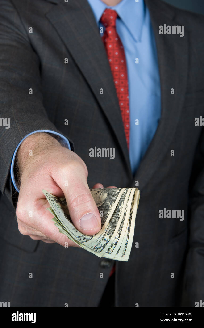 A businessman extending a wad of cash as if offering a payoff or paying for goods. Stock Photo