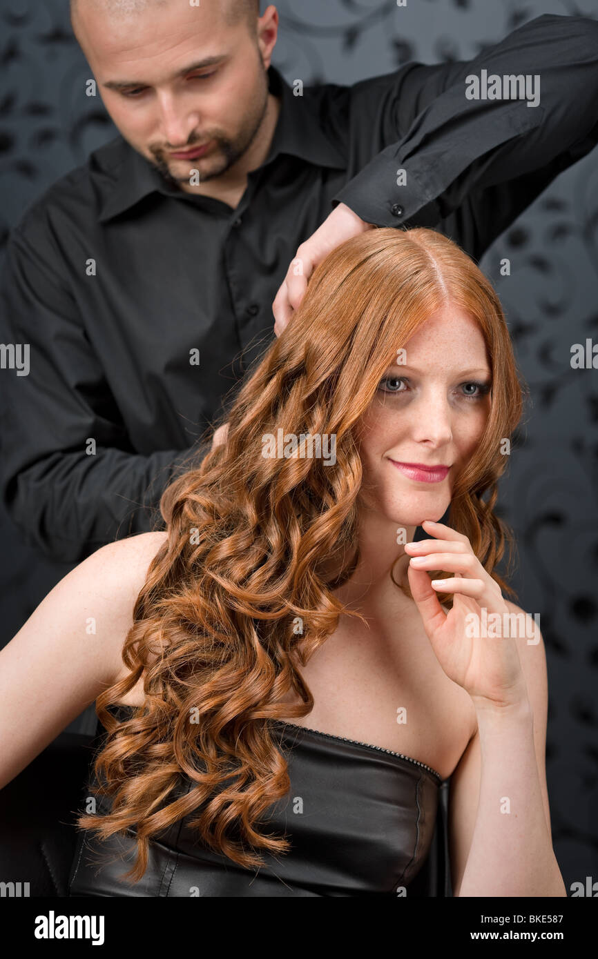 Professional hairdresser with long red curly hair fashion model at