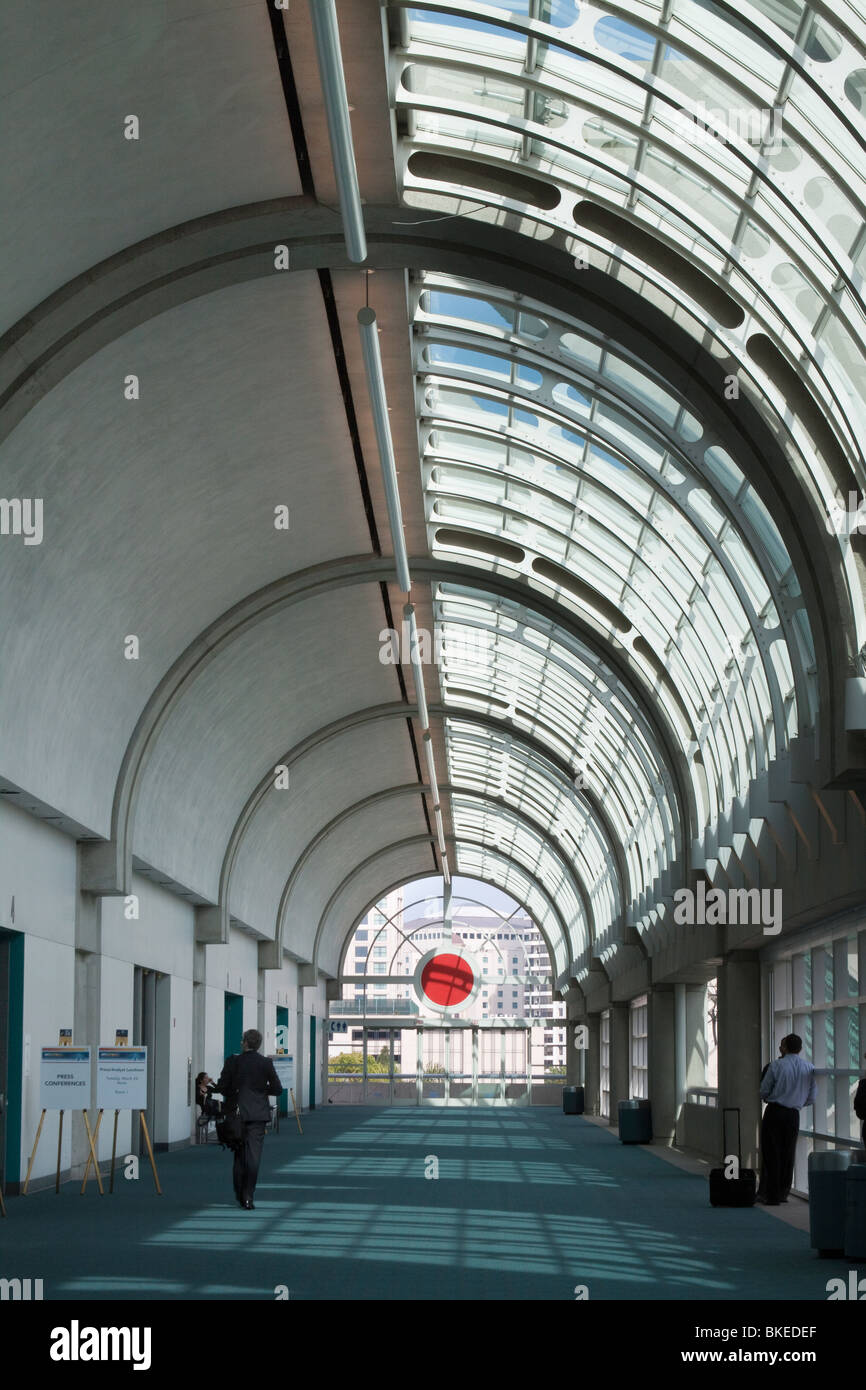 Sparsely populated hallway in San Diego Convention Center with natural light shining through curved glass ceiling Stock Photo