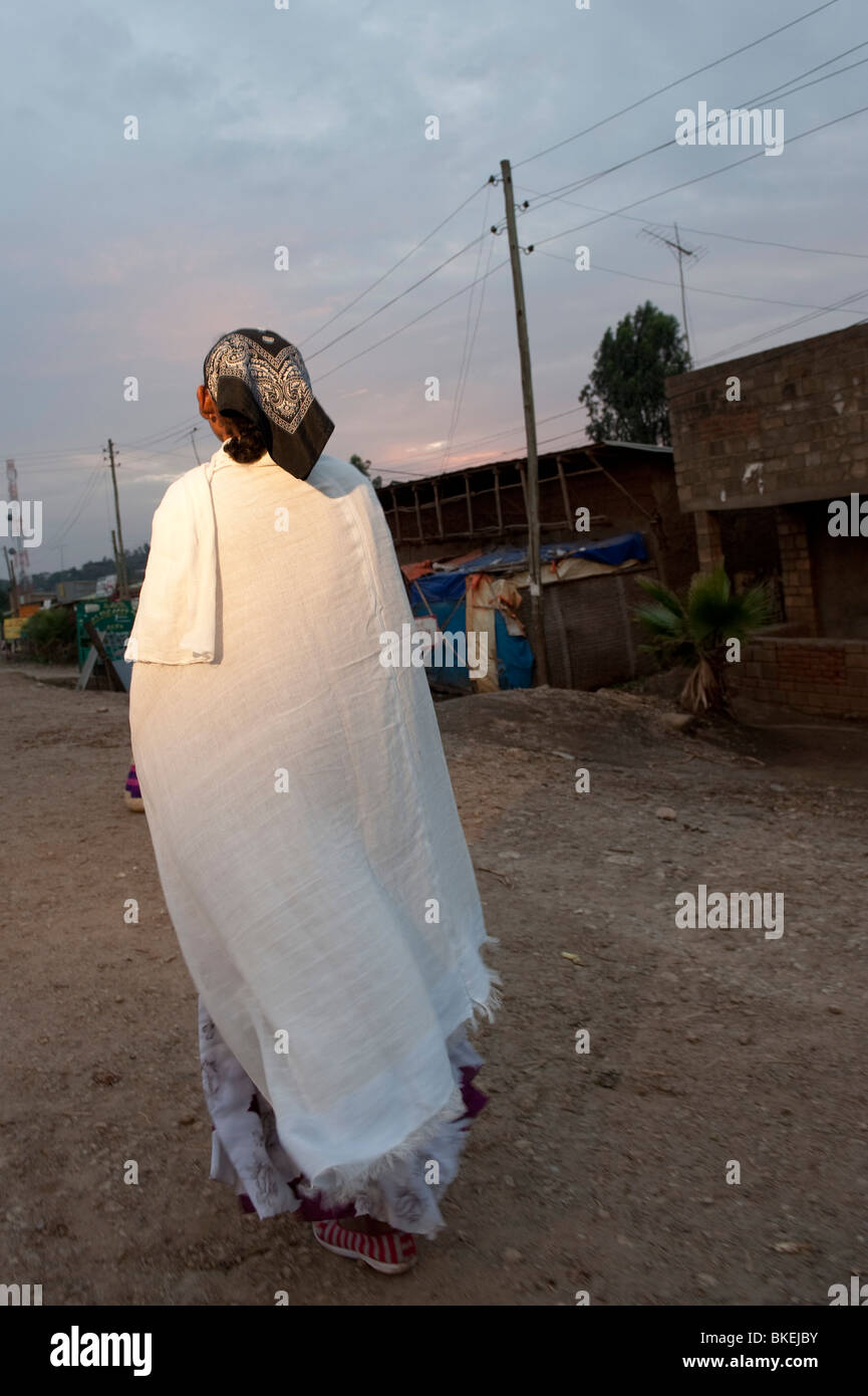 Woman in headscarf walking away from camera on dark street Stock Photo