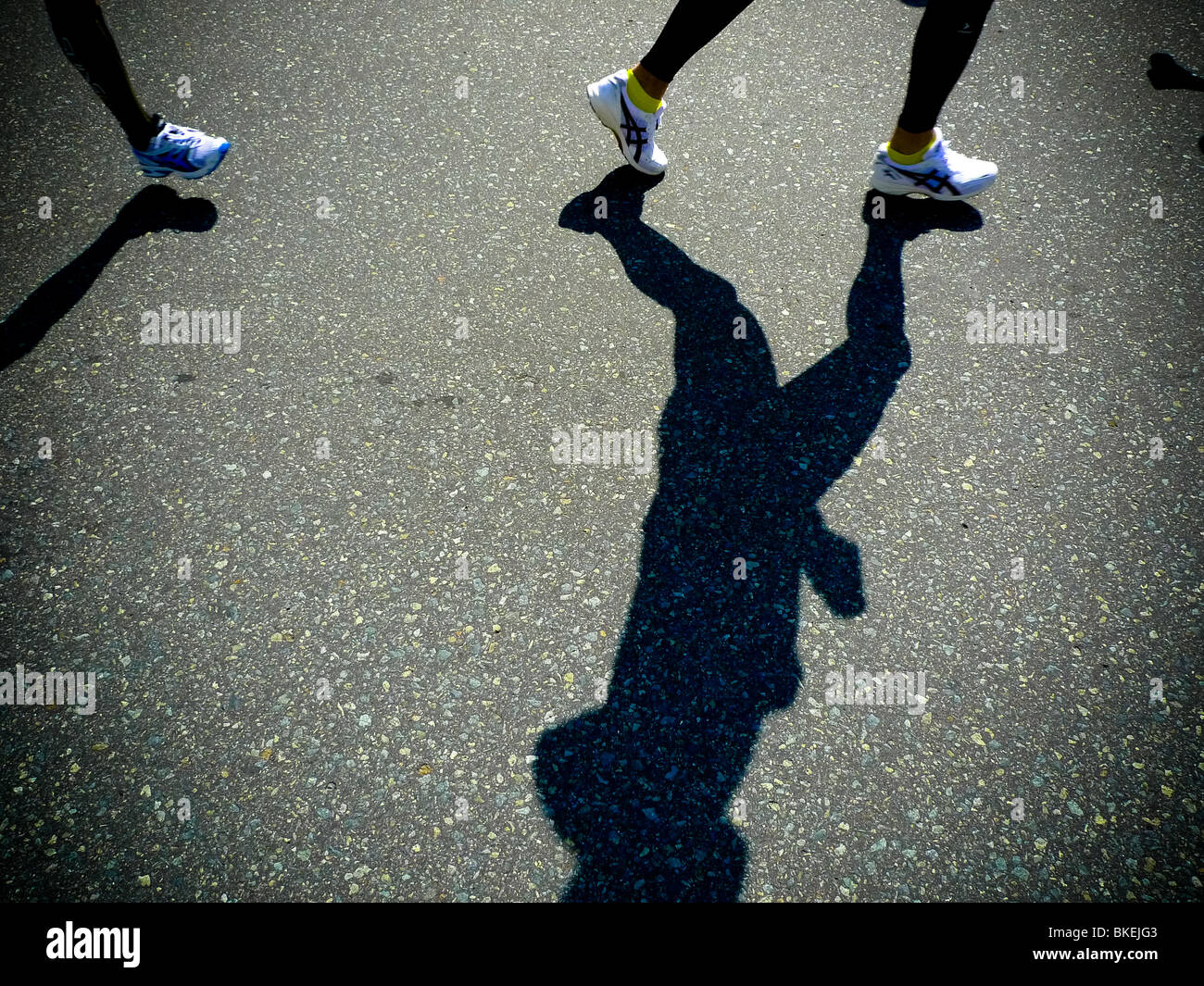 Shadows of runner's legs whilst competing in marathon road race. Stock Photo