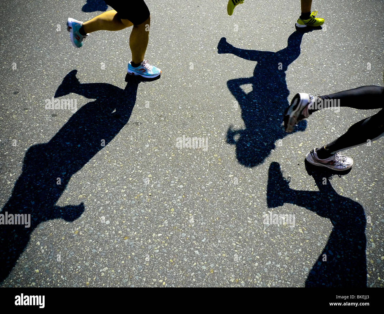 Shadows of runner's legs whilst competing in marathon road race. Stock Photo