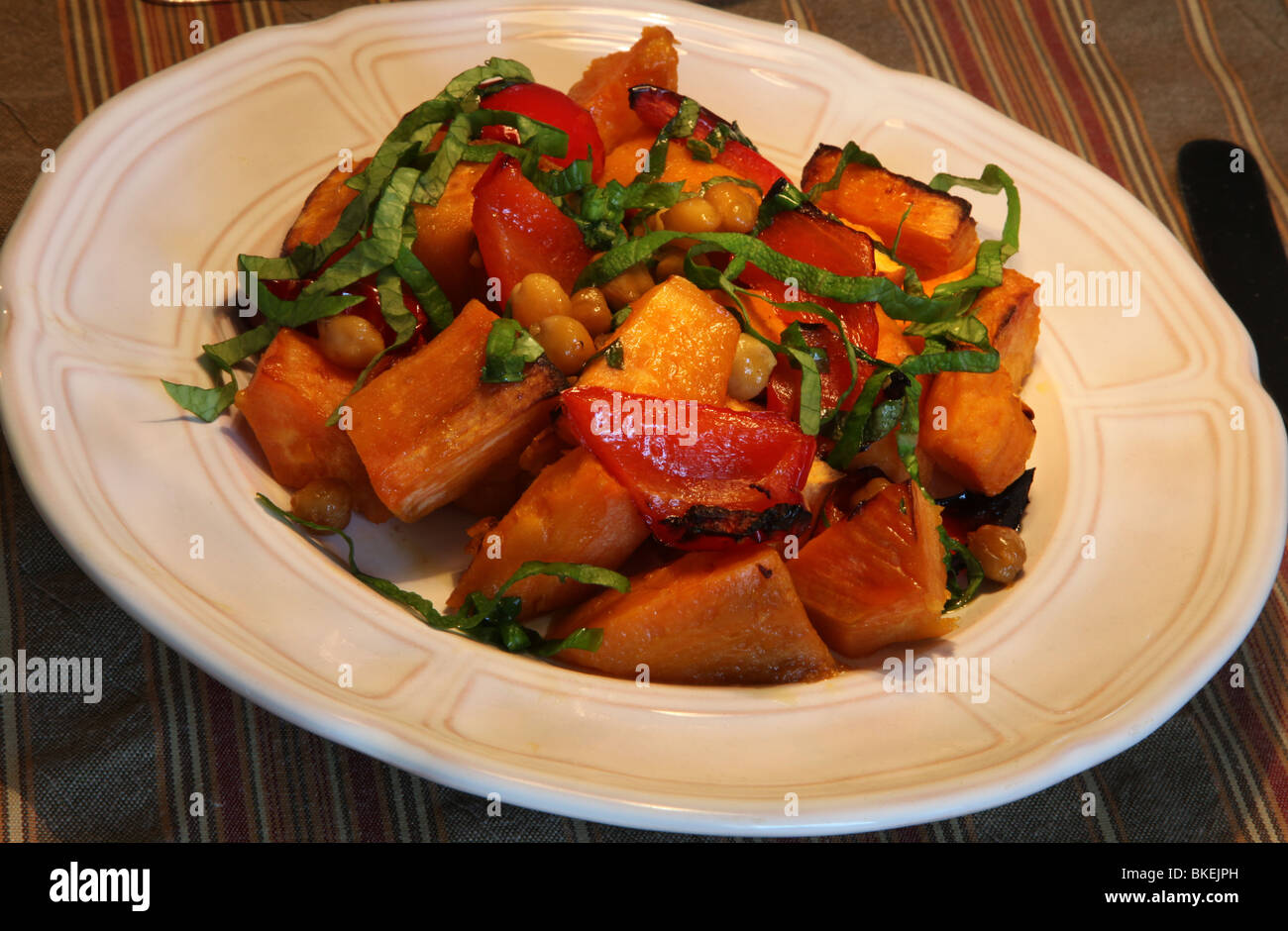 Baked dish of sweet potatoes, red peppers, chick peas and spinach Stock Photo