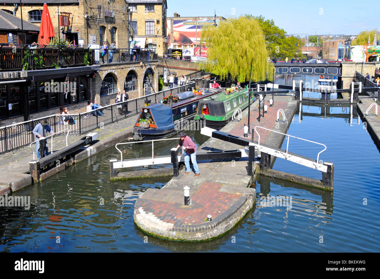 Looking down on lock gates sunny urban landscape & narrowboats in Camden Lock on Regents Canal with weeping willow tree beyond North London England UK Stock Photo