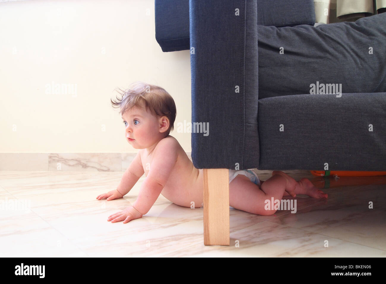 Baby stuck under a sofa Stock Photo
