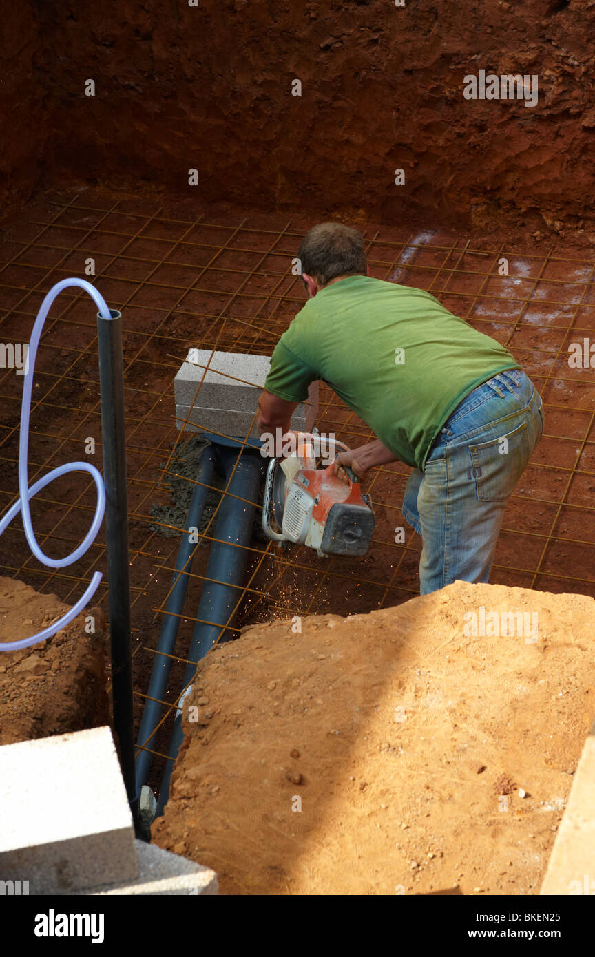 Man building koi pond construction using Stihl to cut base Stock Photo