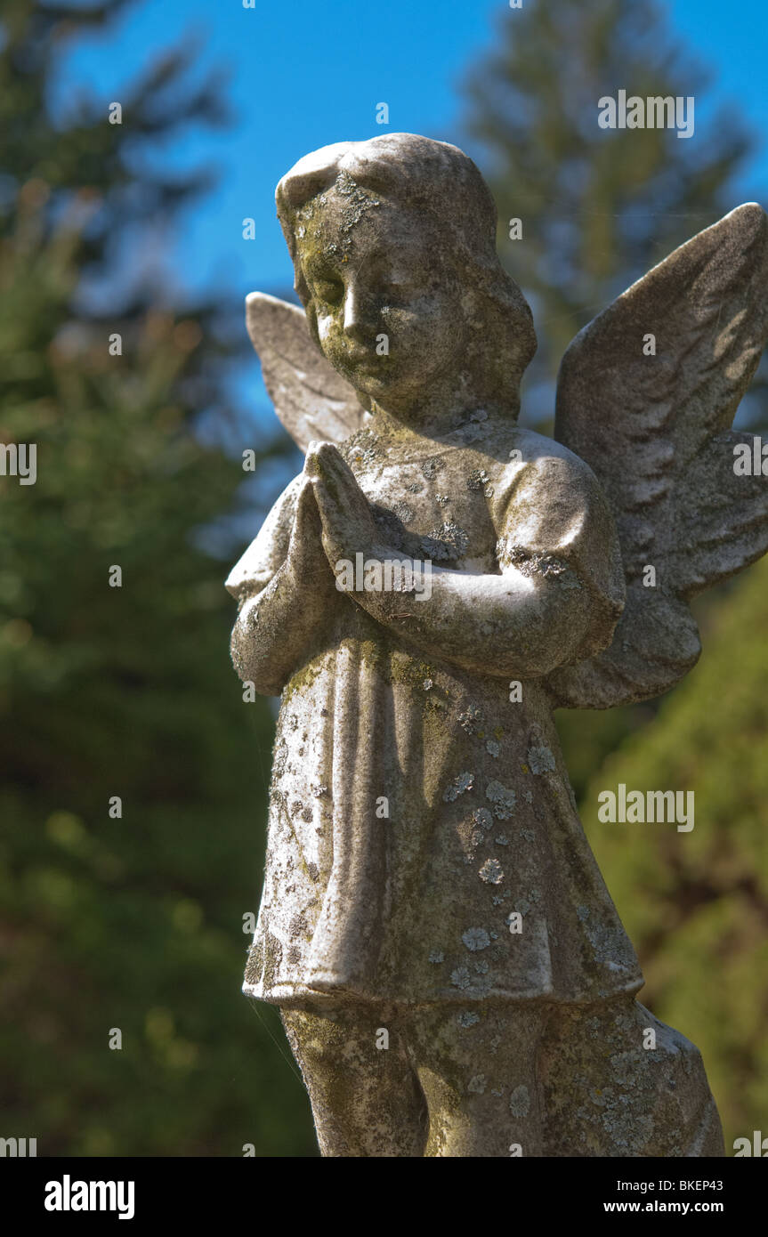 A statue of an angelic child is frozen in time with its' hands clasped