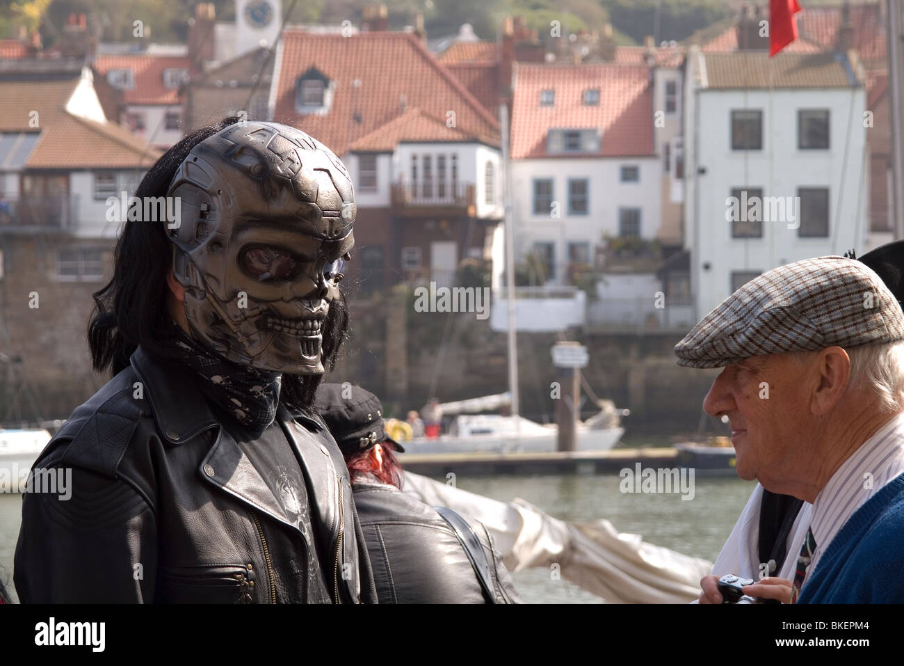 Head and shoulders of a man in a skull mask among passers by at the biannual Goth festival in Whitby Stock Photo