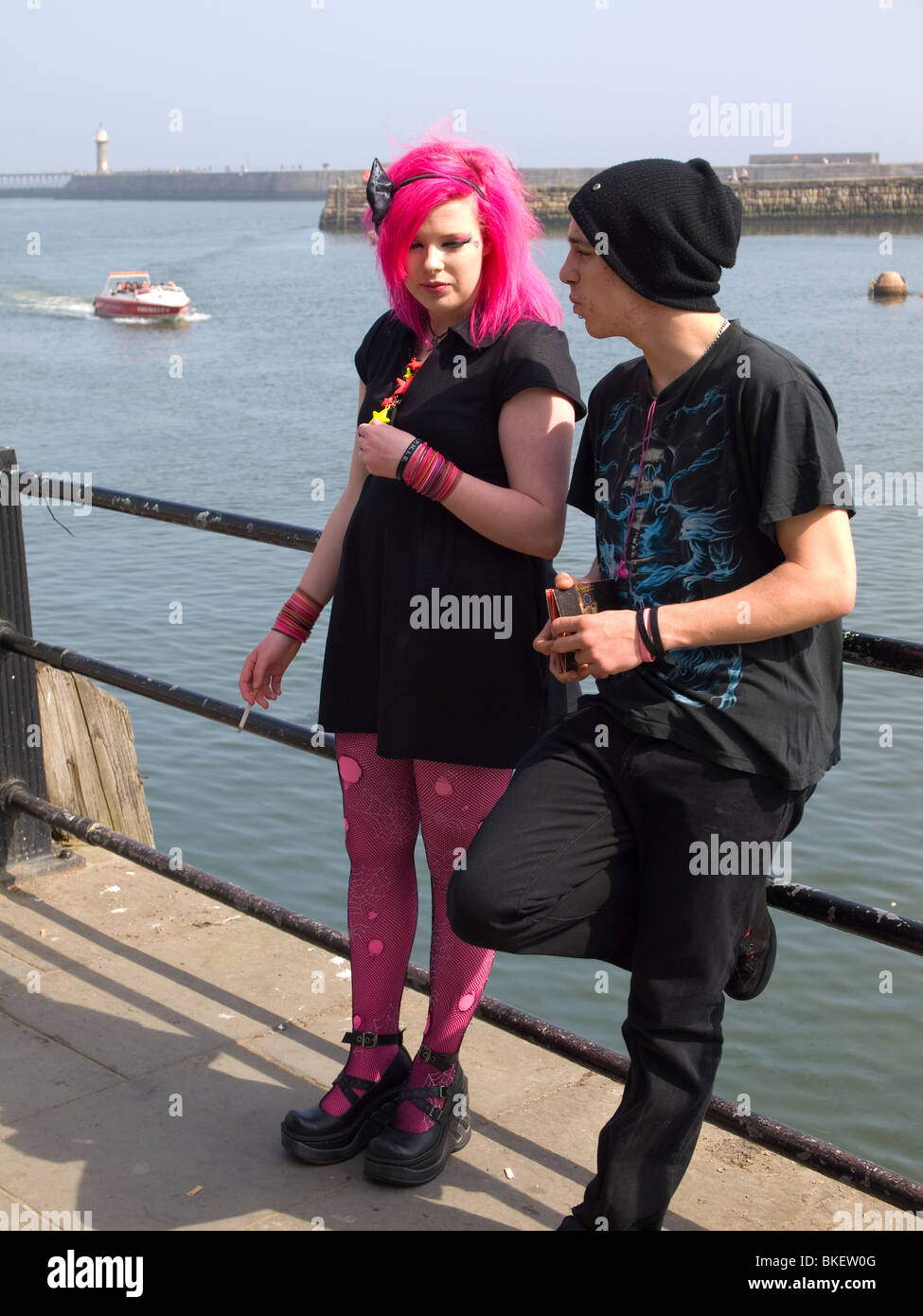 A young couple leaning on the harbour rail at the biannual Goth festival in Whitby Stock Photo