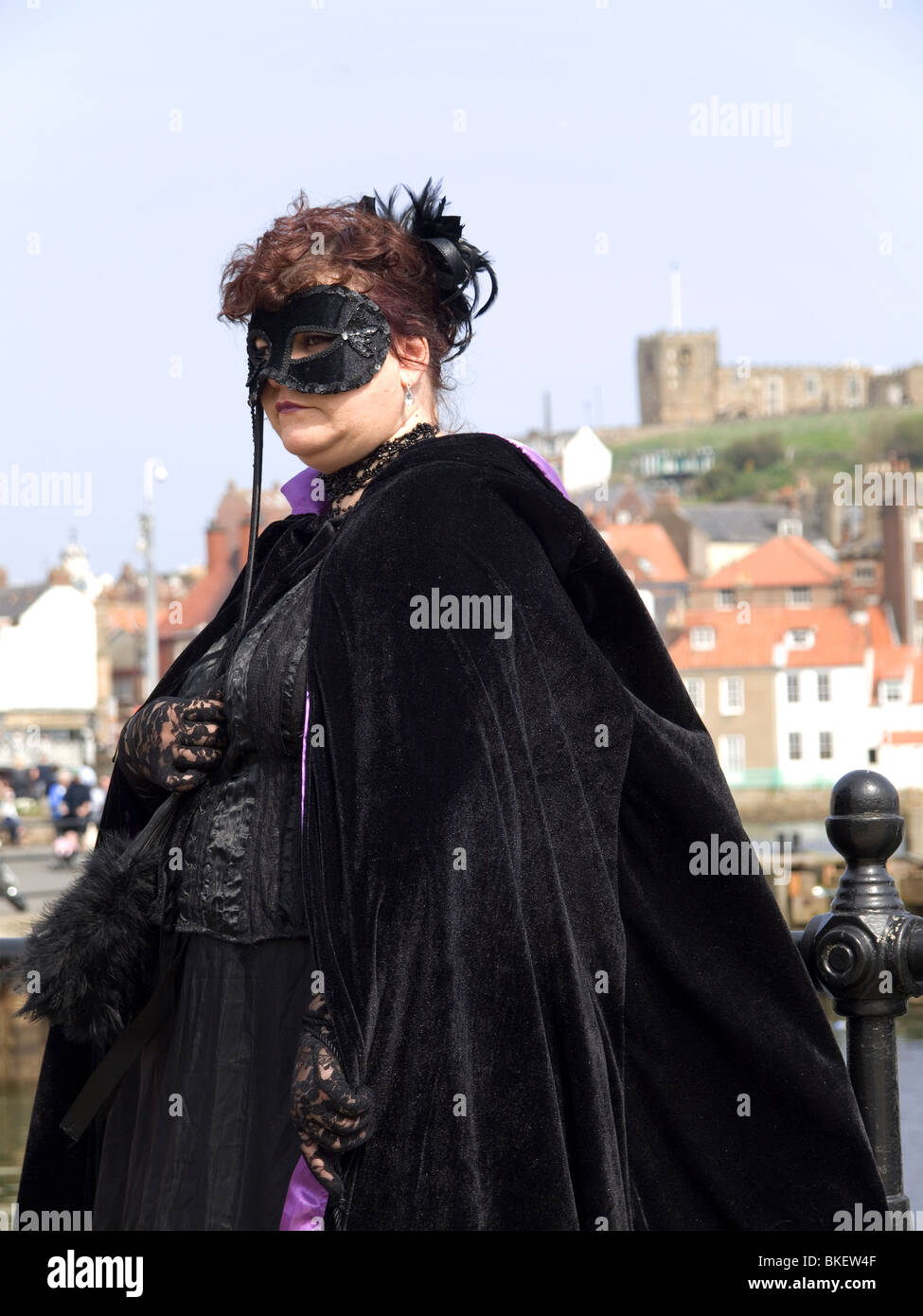 A woman dressed in black fancy dress poses by the harbour at the biannual Goth festival in Whitby Stock Photo