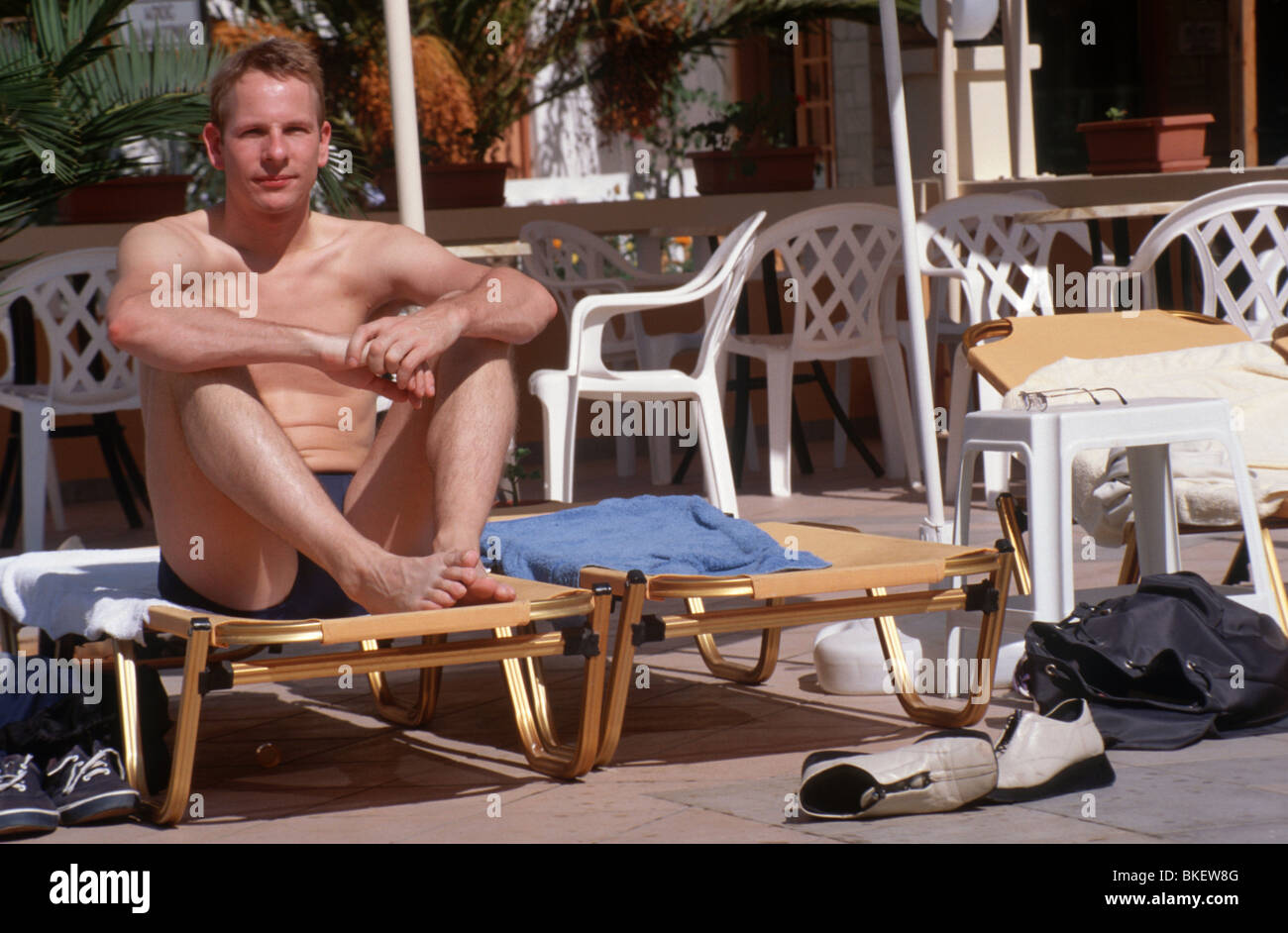 Man on holiday sitting on sunbed Stock Photo