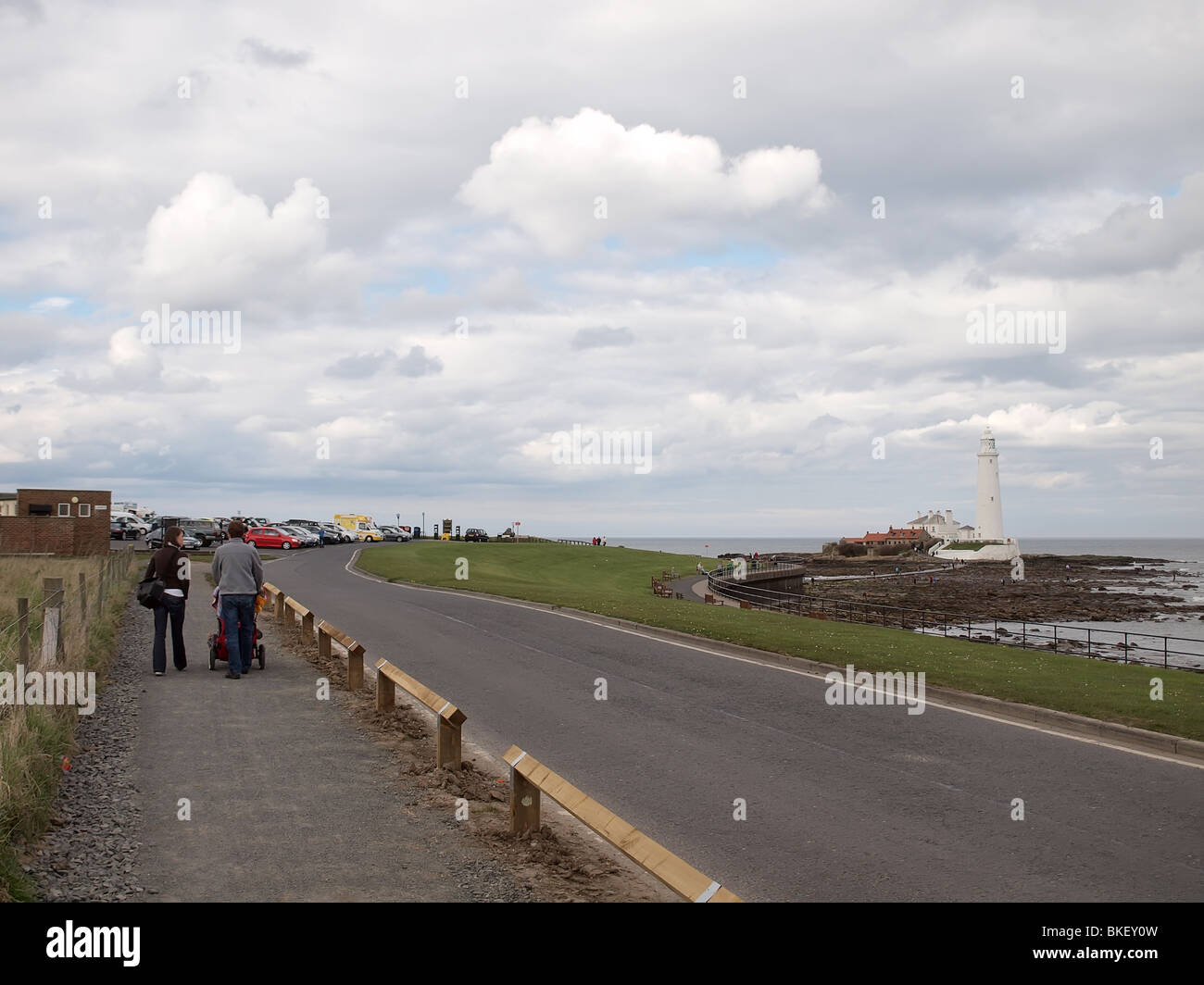 Couple walking in Newcastle upon Tyne on a cloudy day with Whitley Bay lighthouse in the distance Stock Photo