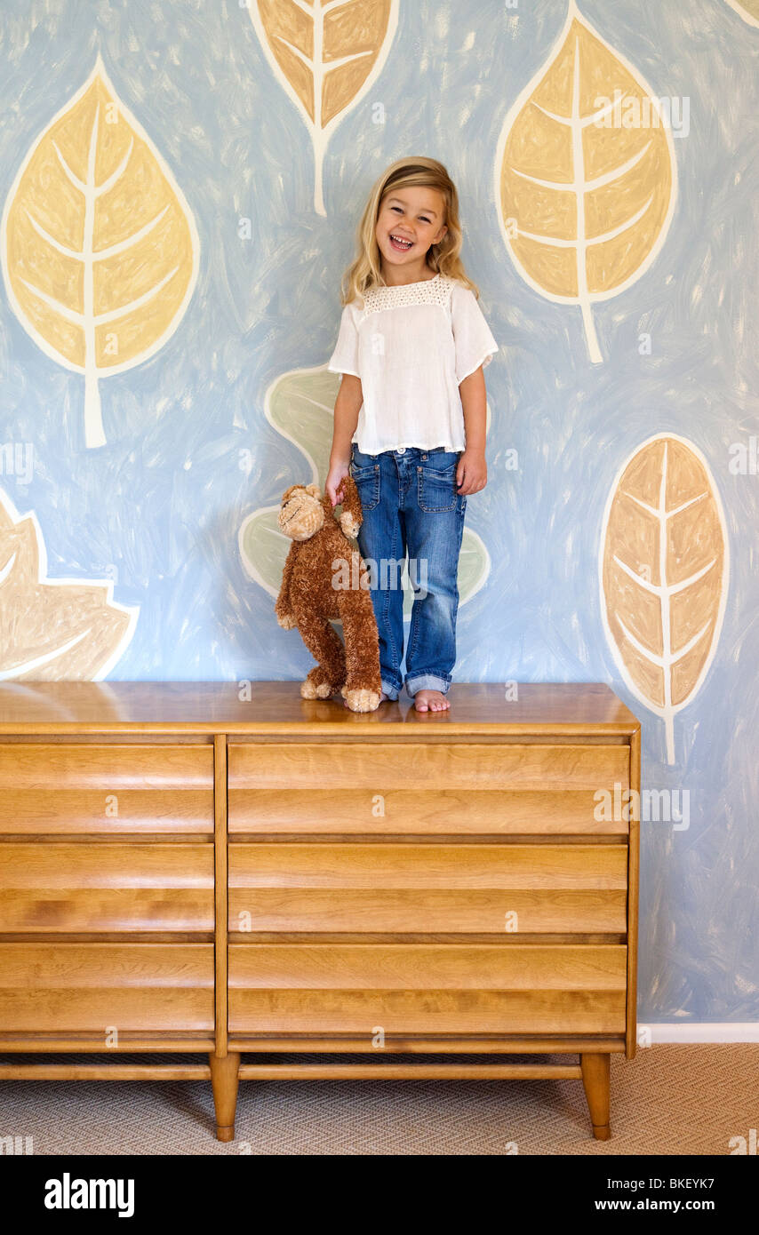 Young girl standing on dresser Stock Photo