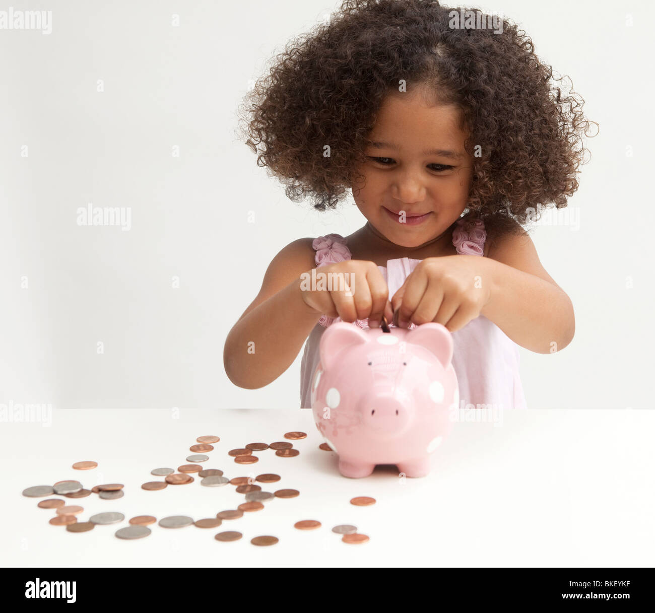 Young girl putting money in piggy bank Stock Photo