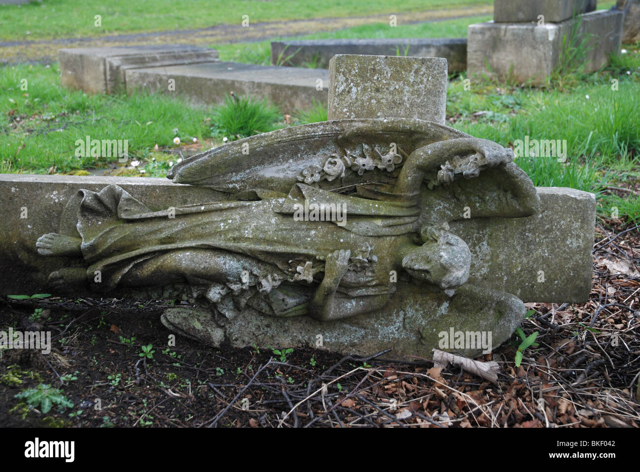 A headstone depicting an angel on a cross, toppled for Health and Safety reasons. Stock Photo