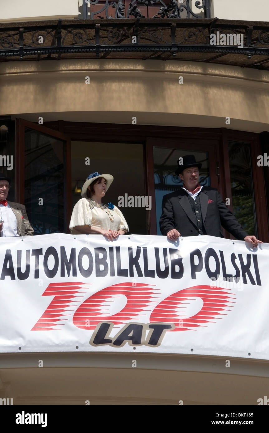 Men and Women on balcony with celebration banner celebrating 100 years of Polish Automobile Club, Bristol Hotel, Warsaw, Poland Stock Photo