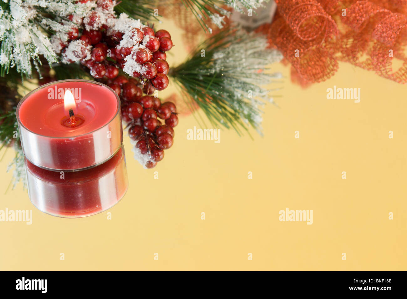 single red tealight candle with snow draped fir branch and red berries with copyspace Stock Photo
