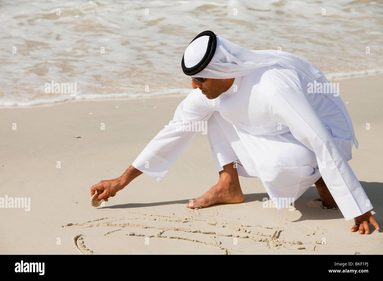 An Arab man wearing traditional dress on a beach in Dubai Stock Photo