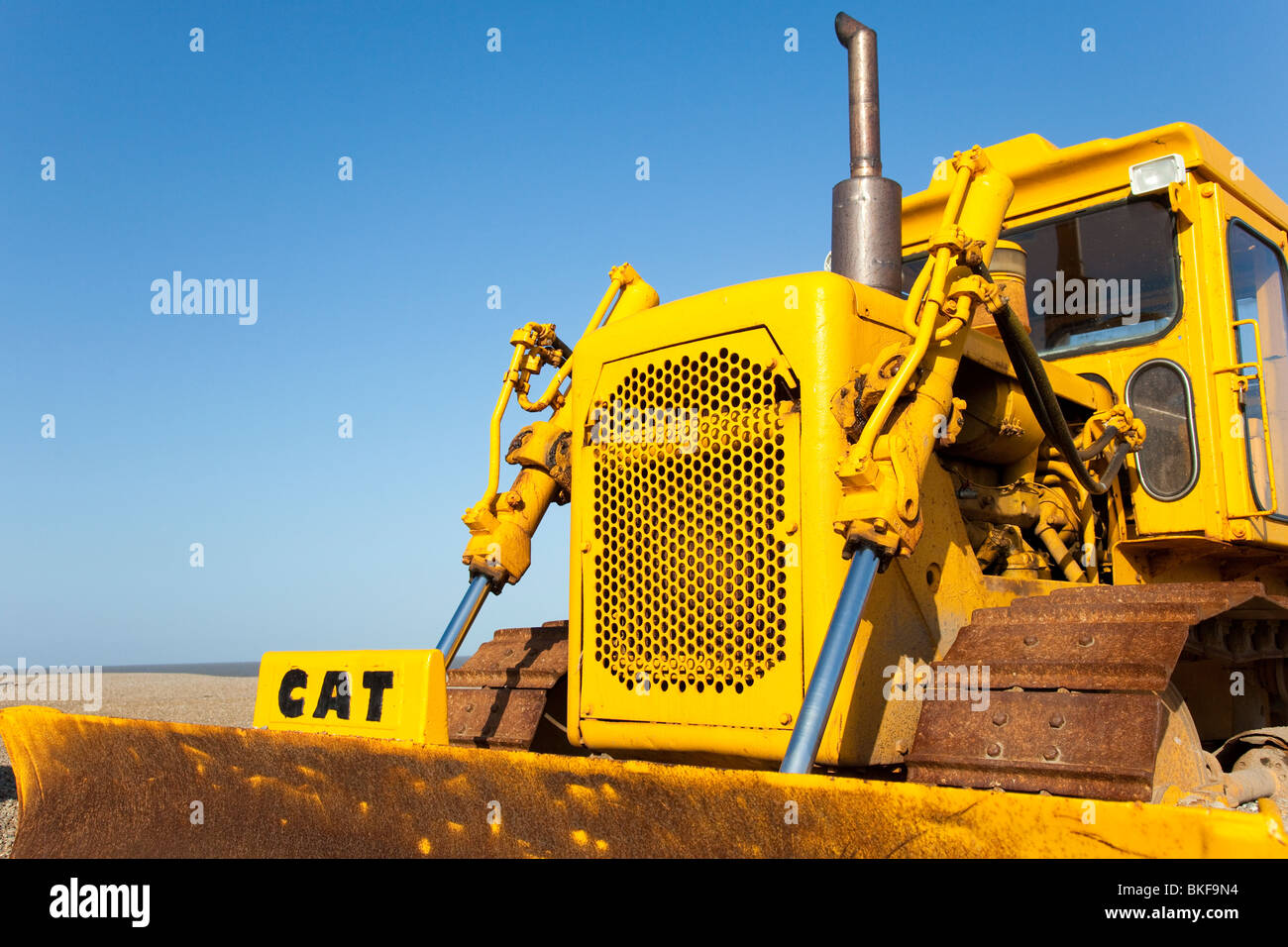 Yellow Caterpillar bulldozer on the beach at Aldeburgh, Suffolk, UK