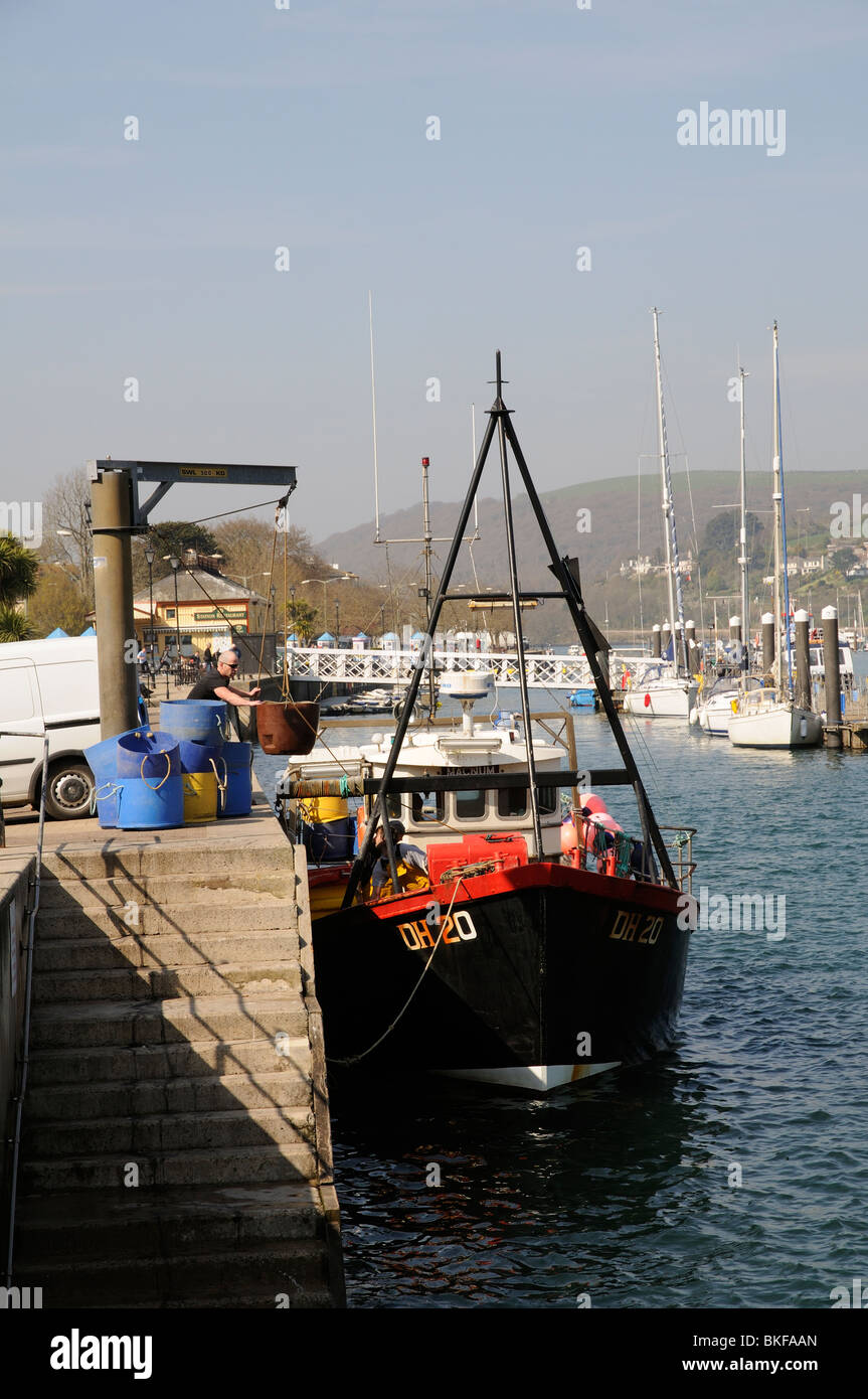 Off loading fish stocks on the quay at Dartmouth south Devon England UK The blue barrels contain seawater stored crabs Stock Photo