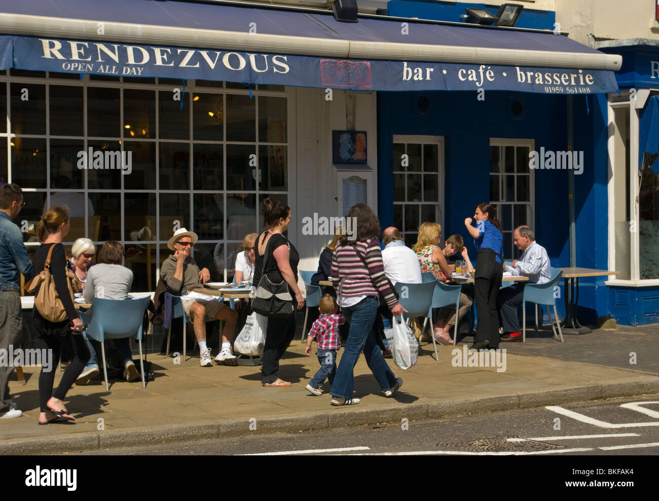 People Relaxing In The Sun at Pavement Tables Of A Cafe Stock Photo