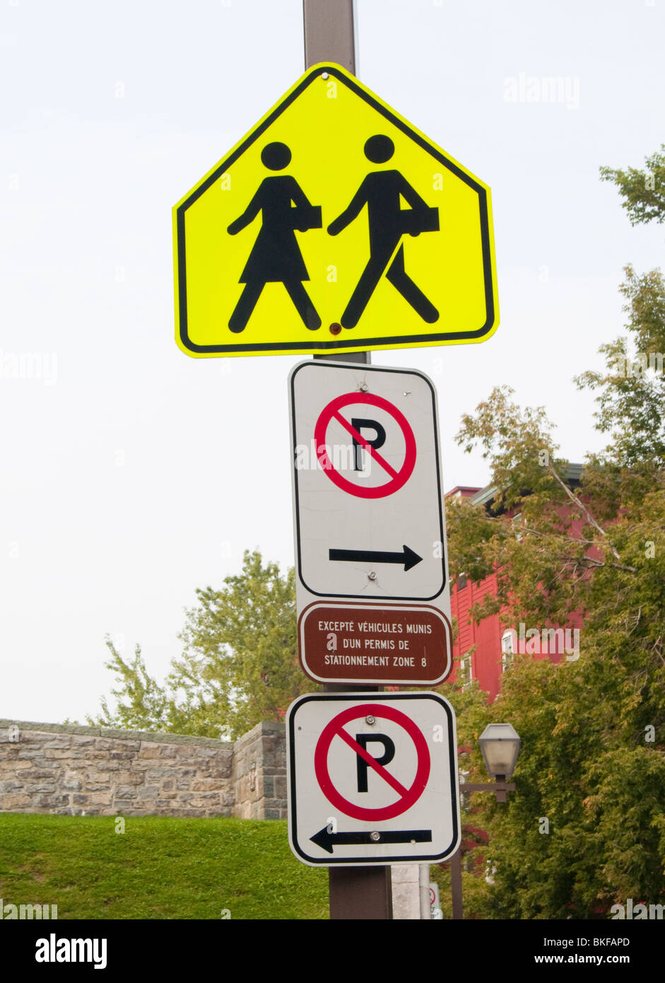 A neon crossing sign and parking restriction notices in Quebec City