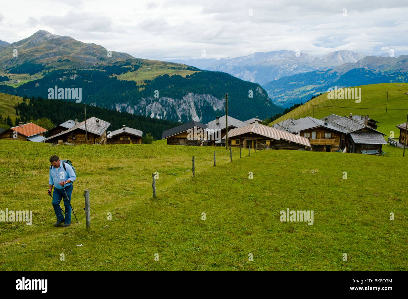 Hiker above the isolated village of Medergen above the Arosa valley, Graubünden, Switzerland Stock Photo