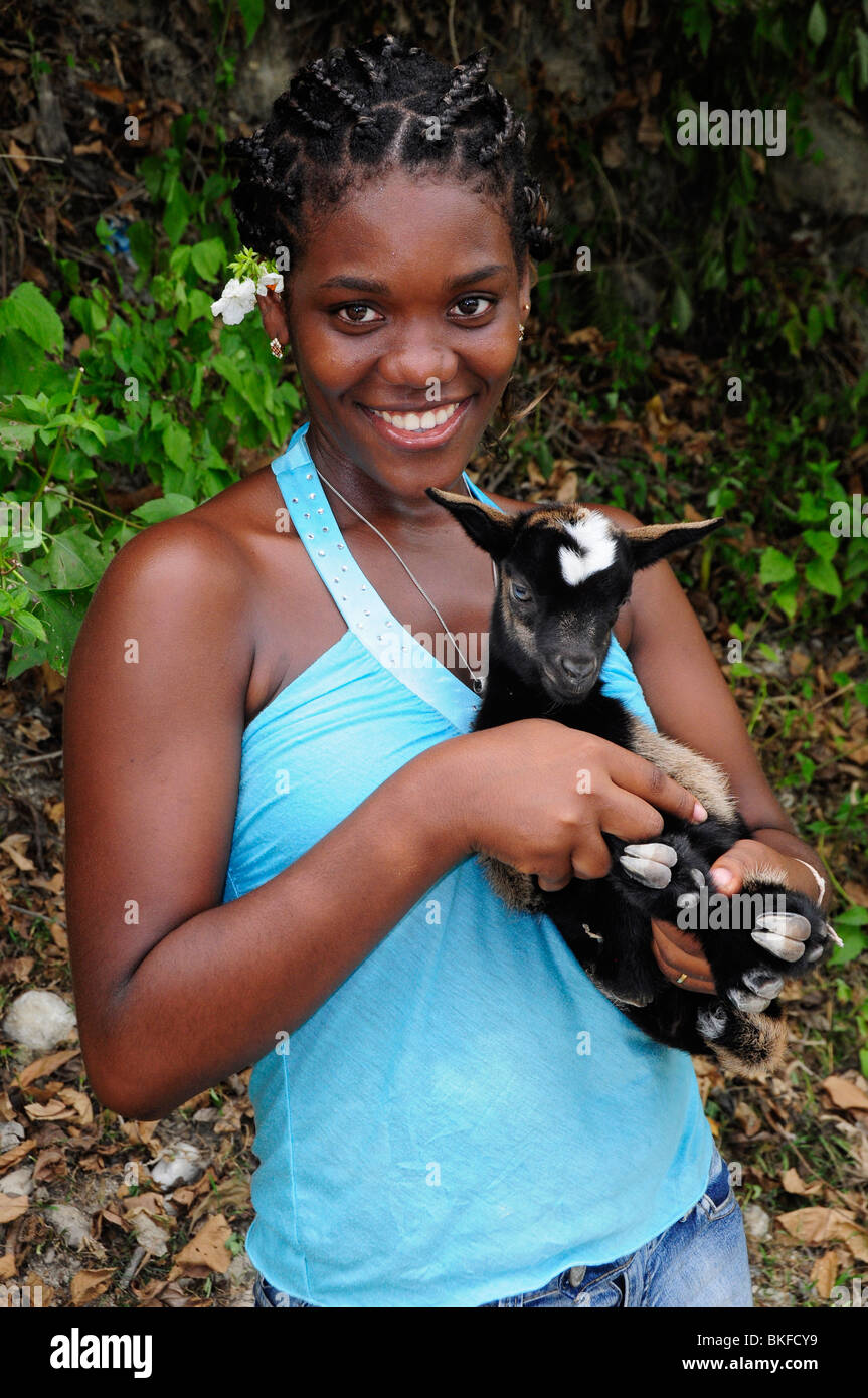Young Haitian girl holding a baby goat, close to the Citadel, Milot, Haiti Stock Photo