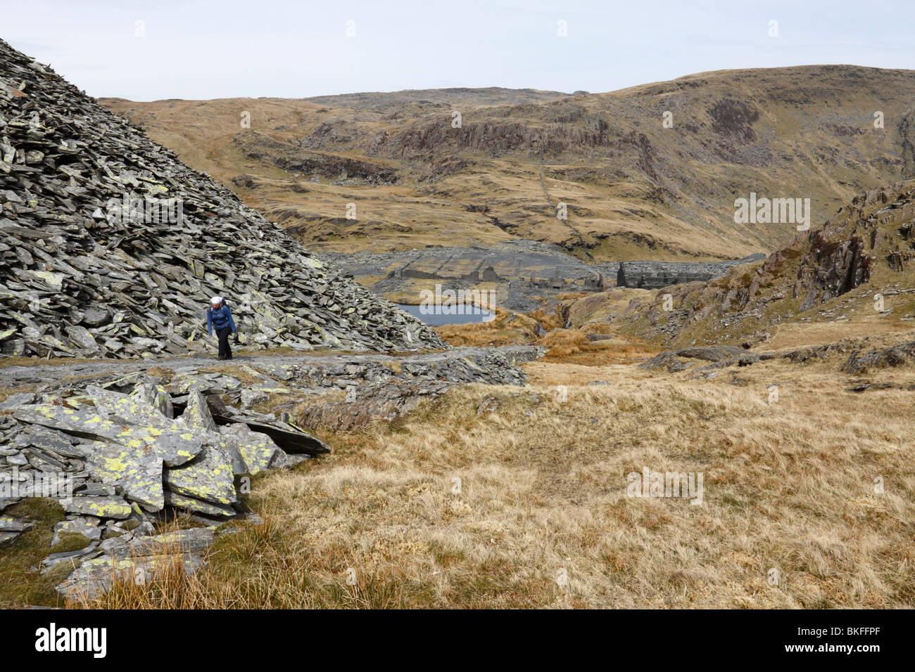 A hill walker climbing an incline on to Moelwyn Mawr from the ruins of the Rhosydd slate mine above Blaenau Ffestiniog in Wales Stock Photo