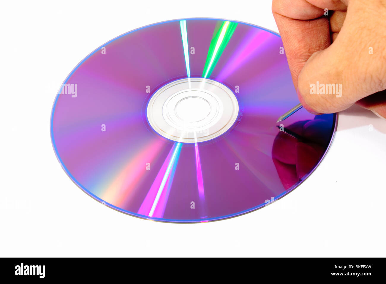 Bottom of a DVD with a nail ready to scratch it Stock Photo