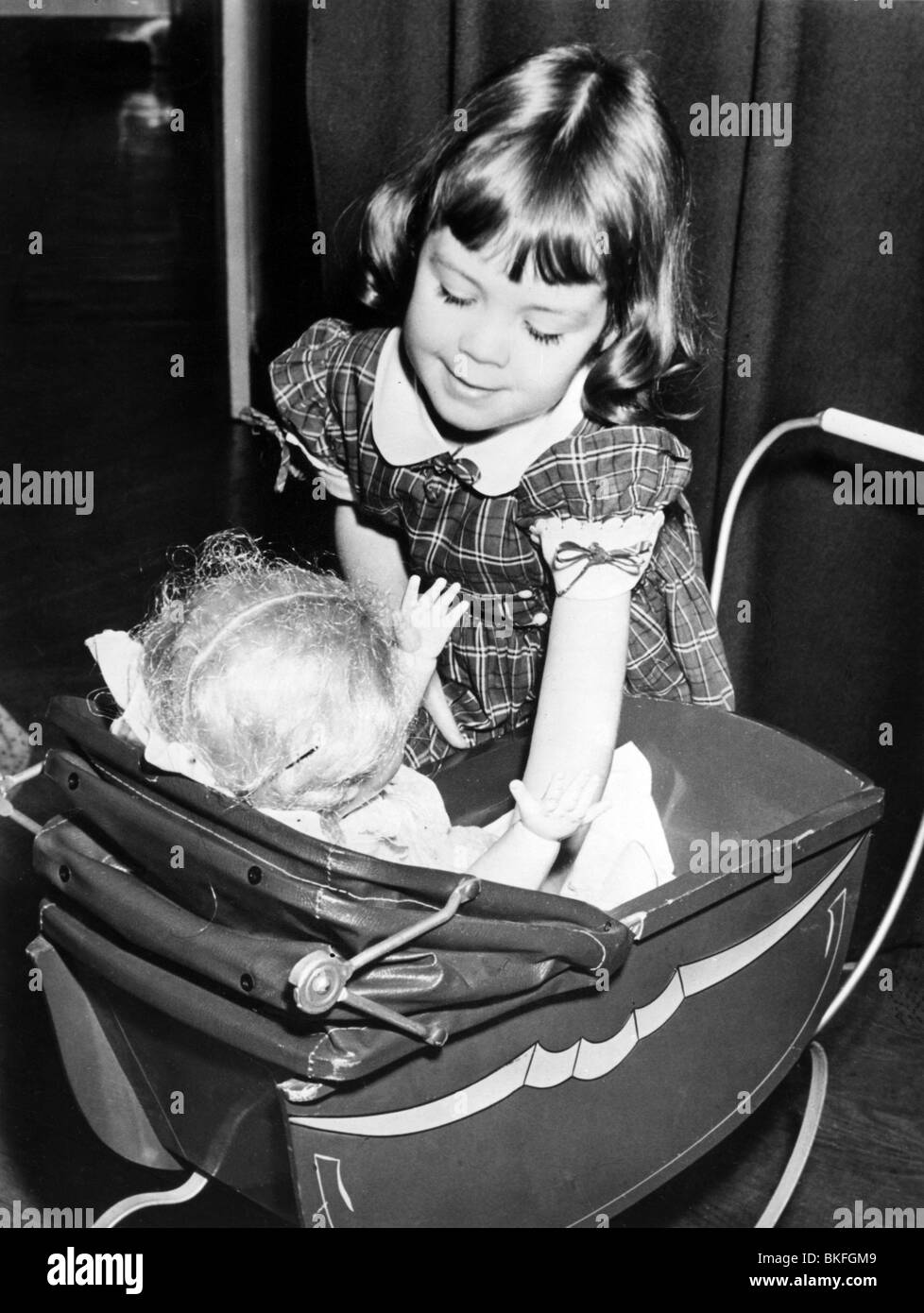 people, child / children, playing, girl putting doll in doll's pram, circa 1960s, , Stock Photo