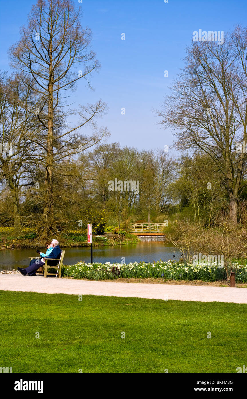 An Elderly Couple Sat On A Bench By The Pond at RHS Wisley Gardens Surrey England Stock Photo