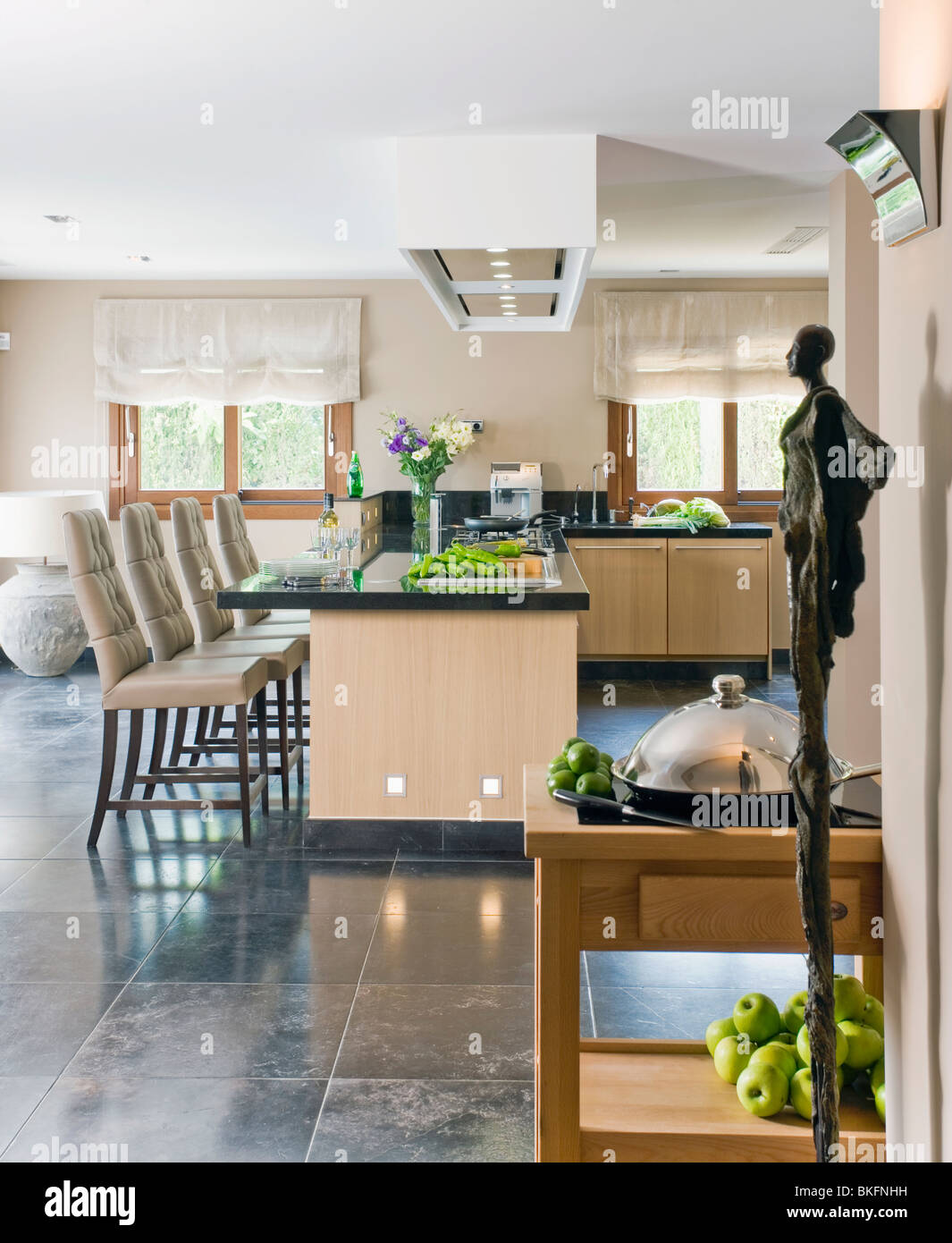 Modern statue in modern kitchen with chairs at breakfast bar on island unit Stock Photo Alamy